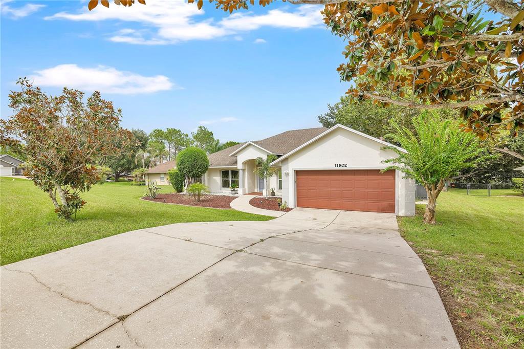 A single-story house with a brown garage door and a concrete driveway — 11802 GRAND HILLS BOULEVARD, CLERMONT, FL