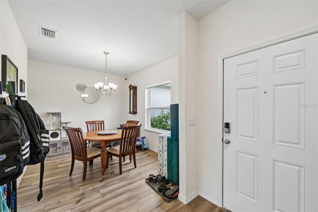 A dining area with a wooden table and chairs sits adjacent to a white front door — 4476 BLACKMAN STREET, NORTH PORT, FL