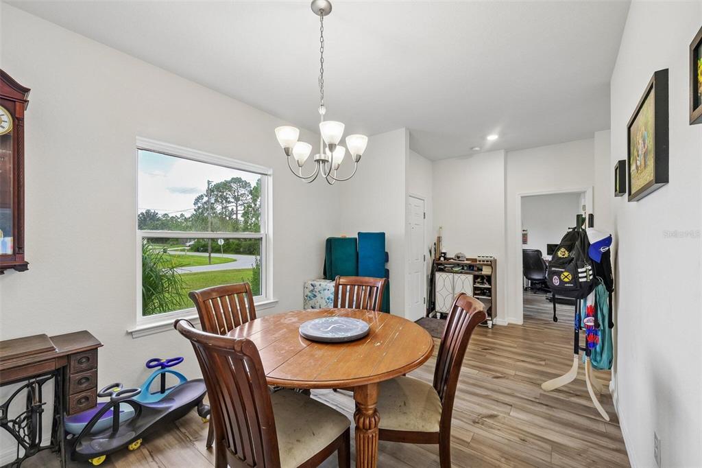 A dining room features a round wooden table, four chairs, and a chandelier — 4476 BLACKMAN STREET, NORTH PORT, FL