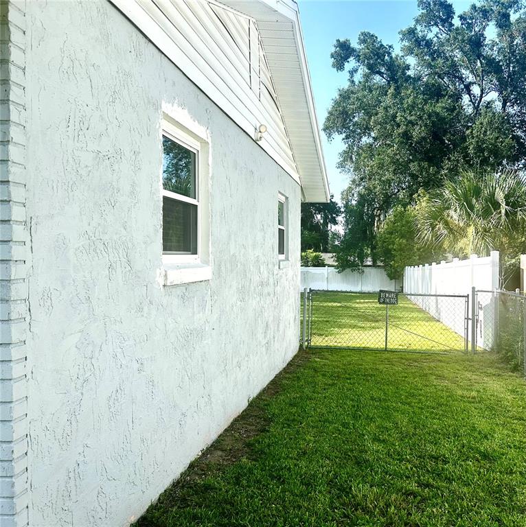 The side exterior of a house features a stucco wall, two windows, and a fenced yard — 3020 SE 11TH STREET, OCALA, FL