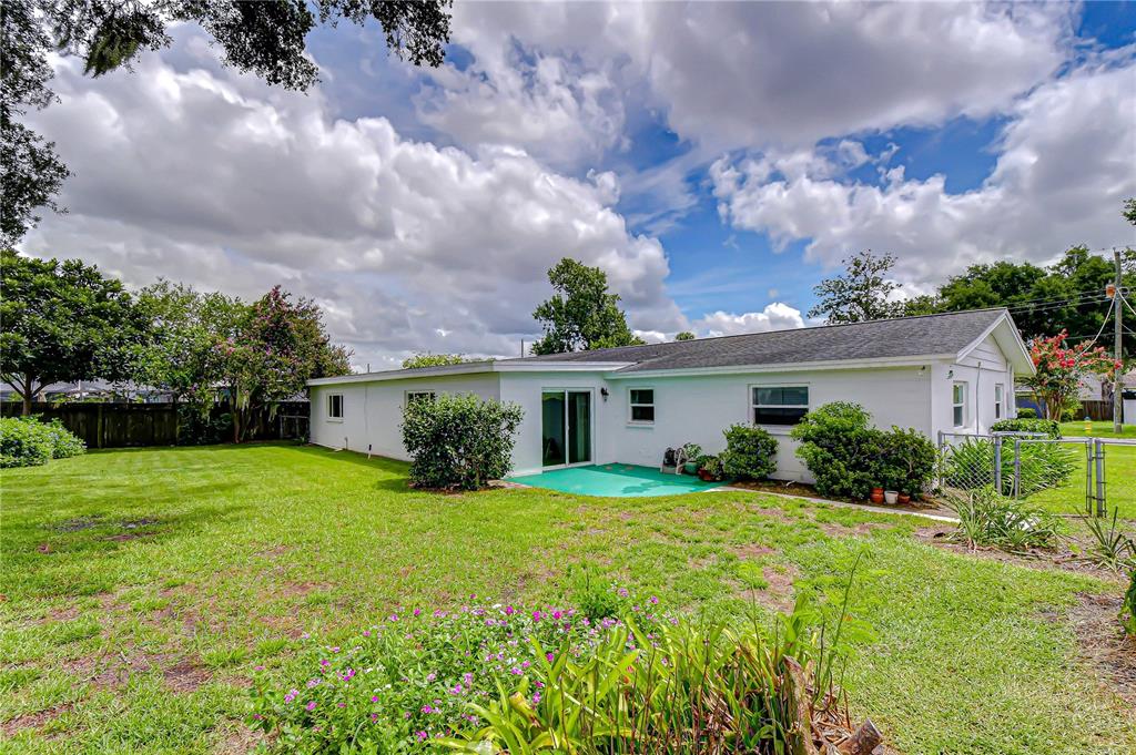 The exterior of a white, single-story house features a green patio and a large backyard — 2205 MALIBU DRIVE, BRANDON, FL
