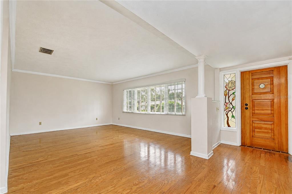 An empty living room with hardwood floors, a large window, and a wood front door — 2205 MALIBU DRIVE, BRANDON, FL