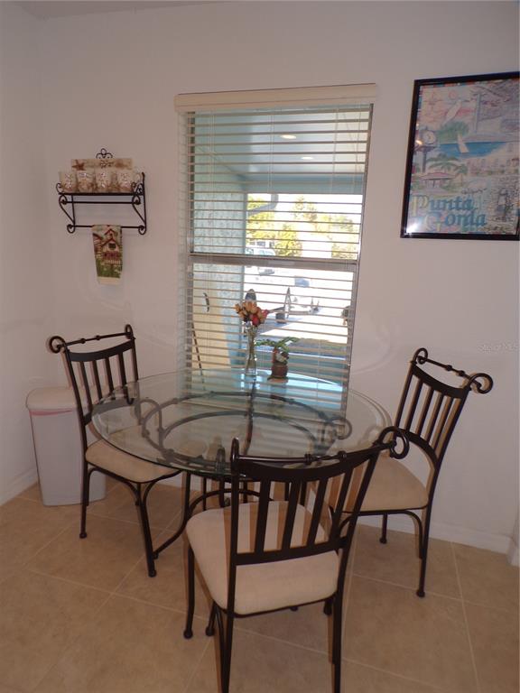 A dining area features a glass-topped table with three chairs, a window, and wall decor — 27097 OMNI LANE, PUNTA GORDA, FL