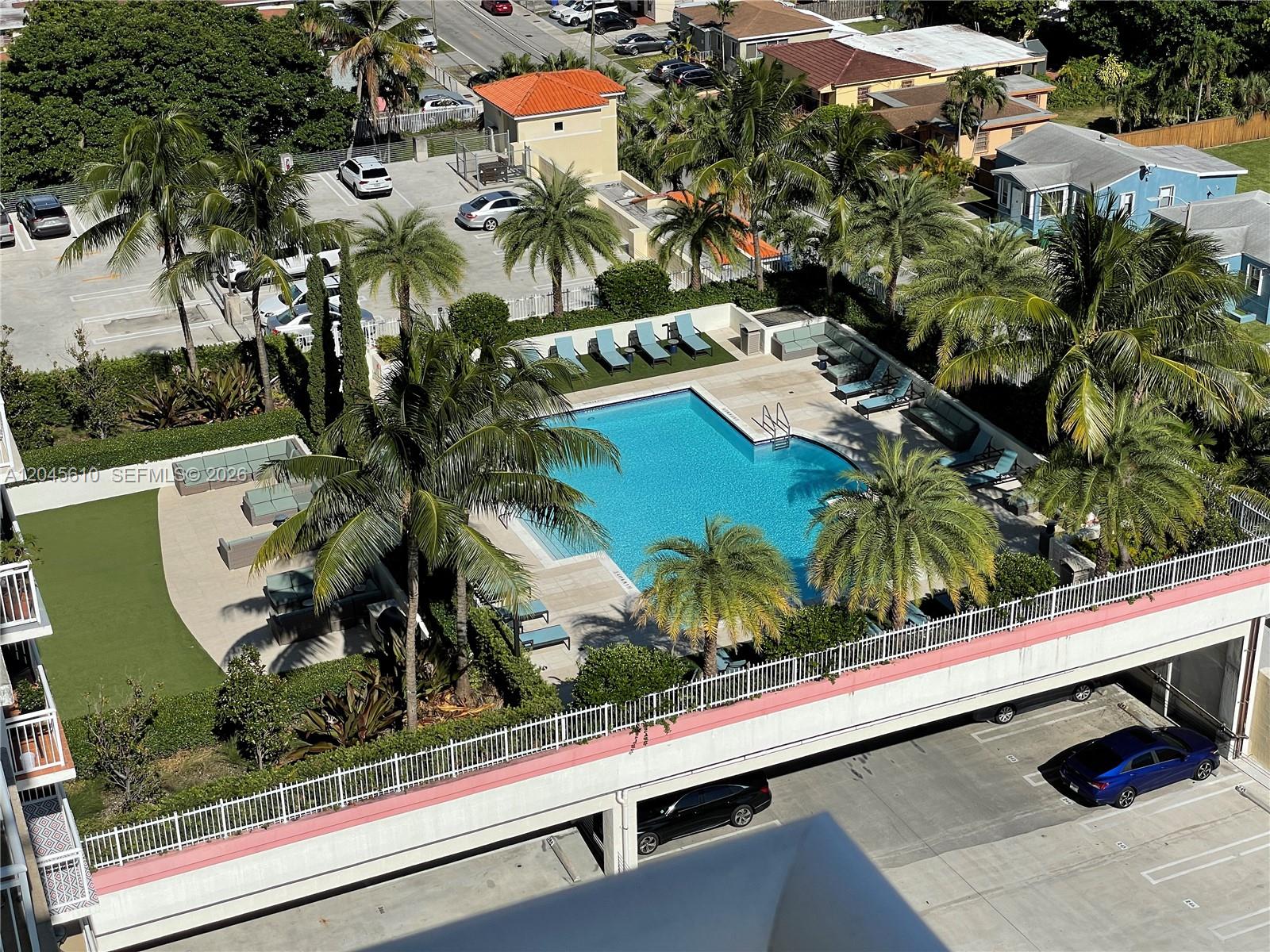 An elevated view shows a swimming pool with lounge chairs and palm trees on a deck — 3000 Coral Way # 1402, Miami FL 33145, MIAMI, FL