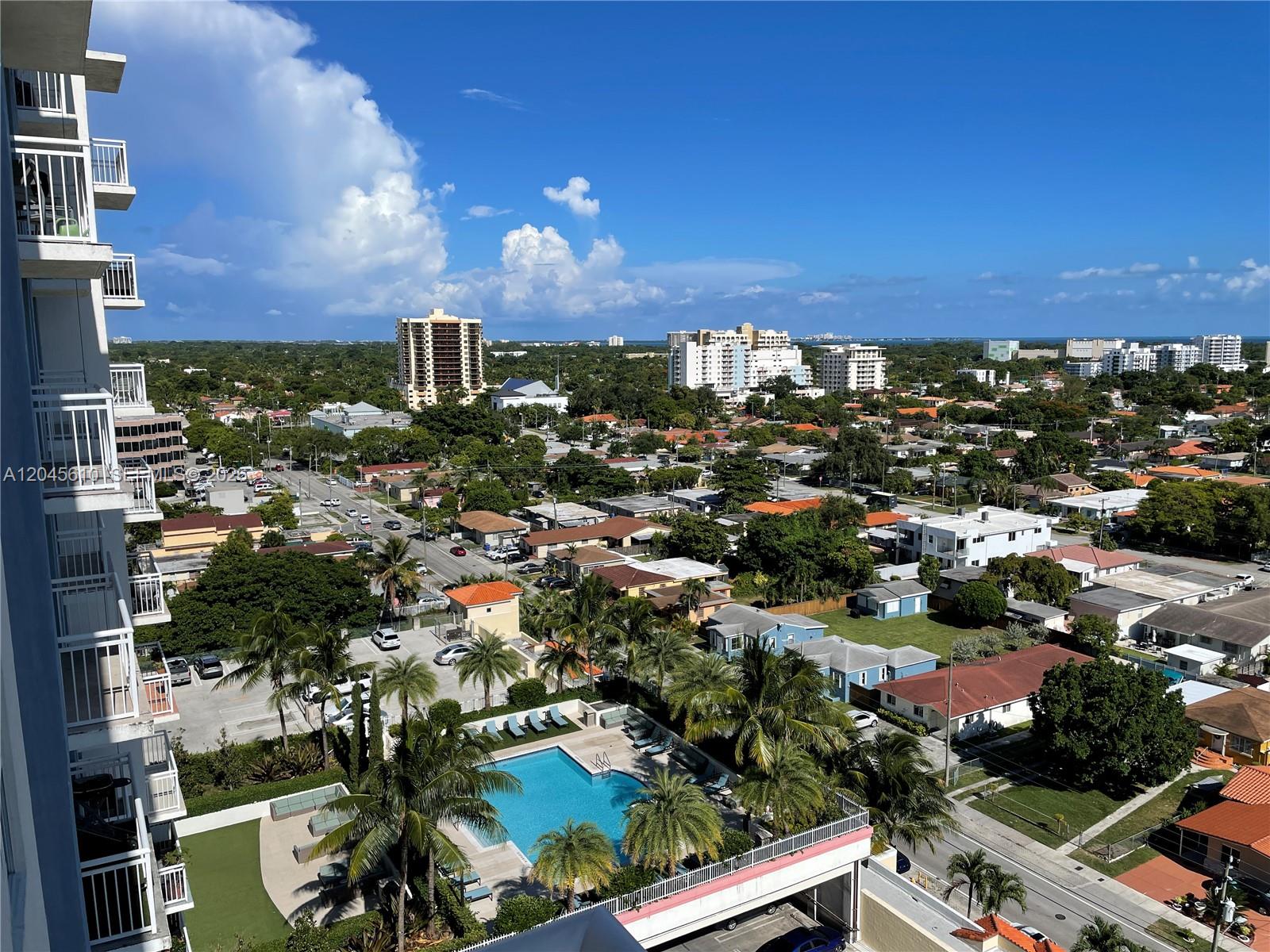 An elevated view shows a residential neighborhood with a swimming pool and distant high-rise buildings — 3000 Coral Way # 1402, Miami FL 33145, MIAMI, FL