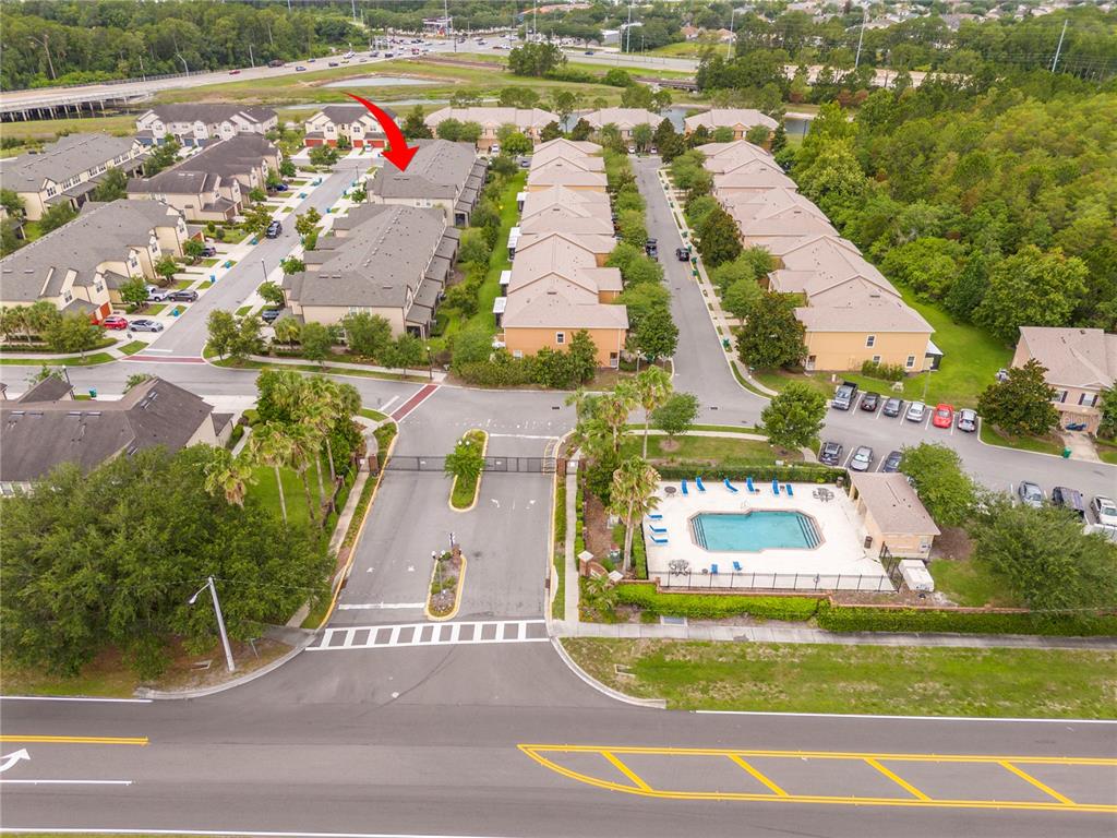 An aerial view shows a gated residential townhouse community with a swimming pool and parking — 519 VIRTUOSO LANE UNIT 77, ORLANDO, FL