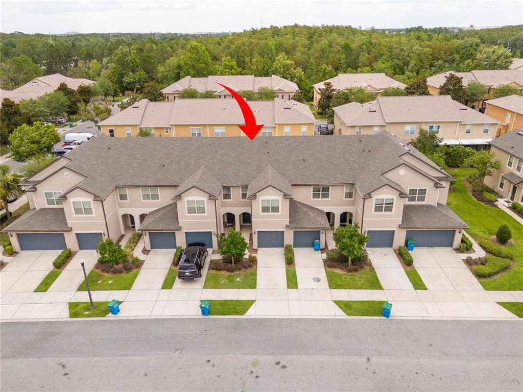 An aerial view shows a multi-unit townhouse building with a shingled roof and garages — 519 VIRTUOSO LANE UNIT 77, ORLANDO, FL