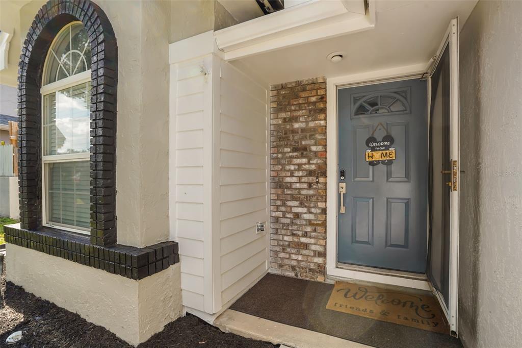 The exterior entryway features a blue front door, brick accents, and a white-trimmed arched window — 1032 NIN STREET, ORLANDO, FL