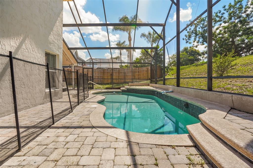 A screened-in swimming pool with a paver patio and a wooden fence in the background — 1032 NIN STREET, ORLANDO, FL