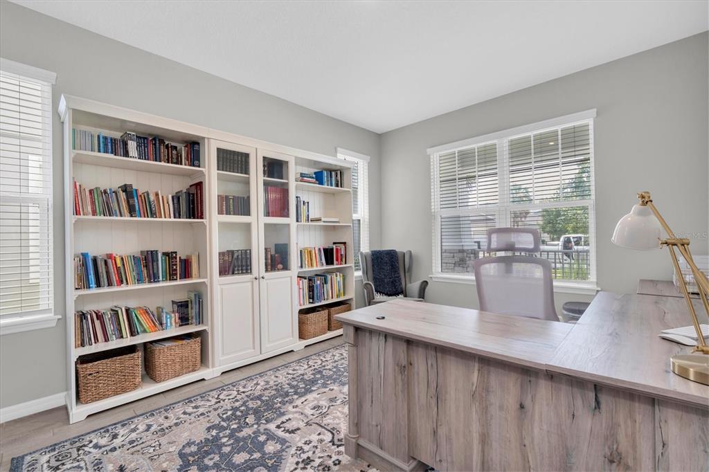 A home office features a large wooden desk, built-in white bookshelves, and a patterned area rug — 13709 STANSIL AVENUE, ODESSA, FL