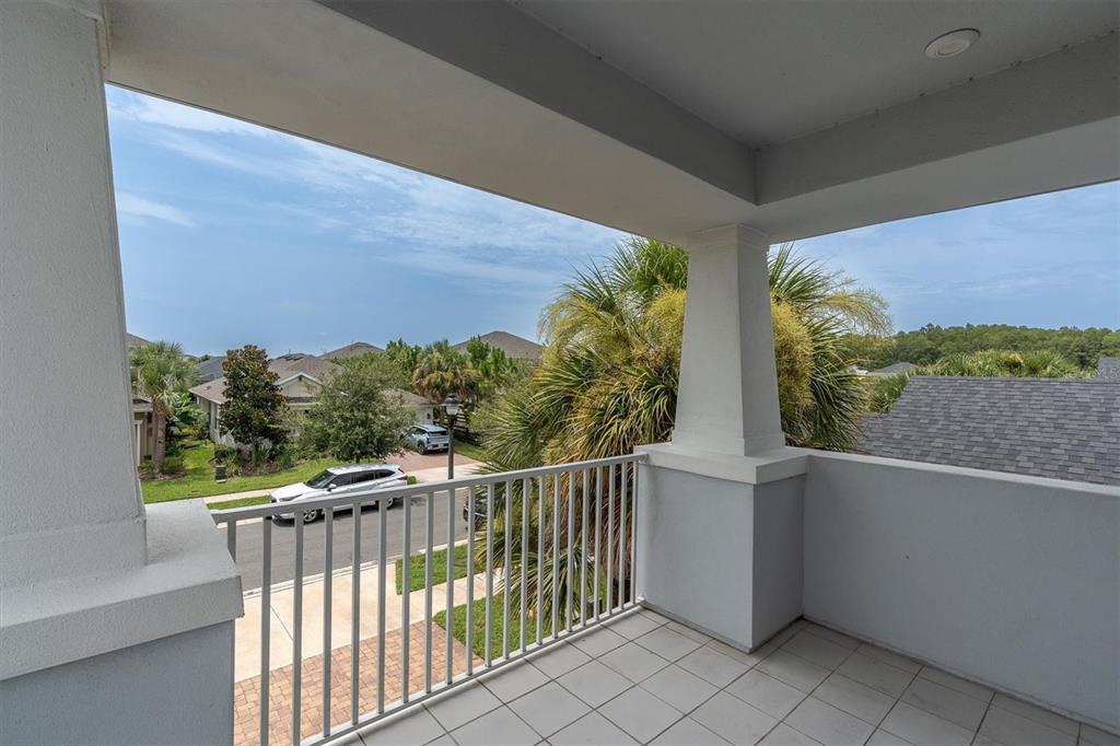A covered balcony with white railings overlooks a suburban street and palm trees — 13709 STANSIL AVENUE, ODESSA, FL