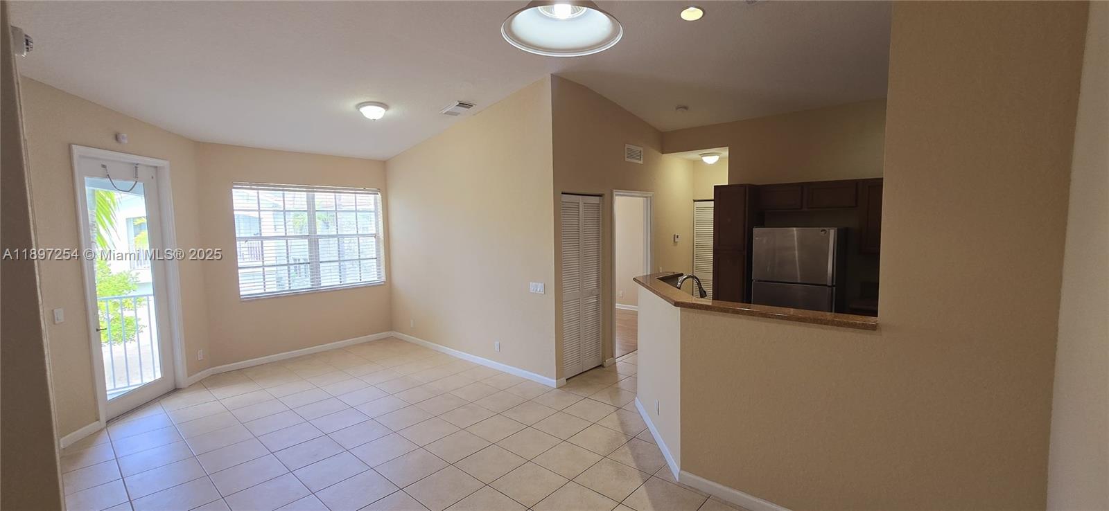 This living area features tile flooring, a sliding glass door, and an open kitchen — 3020 Laurel Ridge Cir, Riviera Beach FL 33404, RIVIERA BEACH, FL