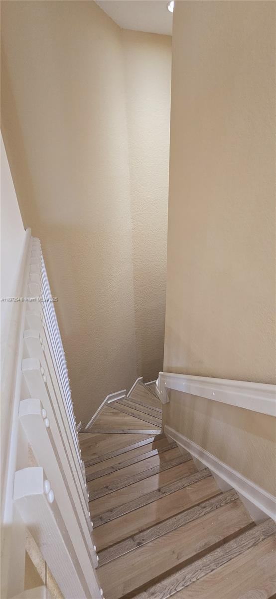 A wooden staircase with a white railing descends between two beige walls — 3020 Laurel Ridge Cir, Riviera Beach FL 33404, RIVIERA BEACH, FL