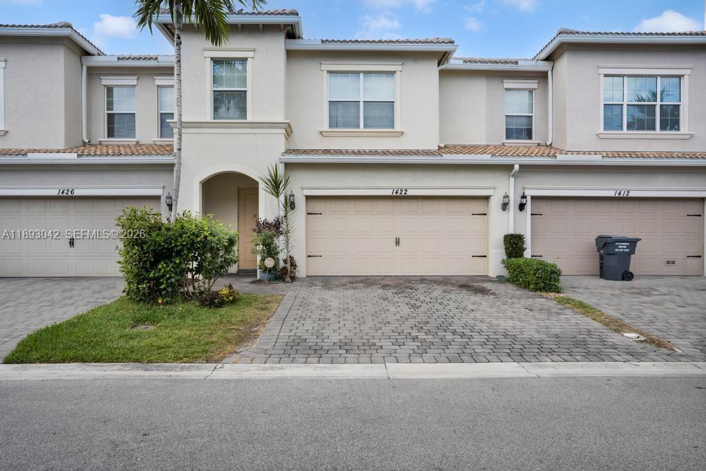 A row of three beige townhouses with paved driveways and attached garages under a blue sky — 1422 Silk Oak Dr, Hollywood FL 33021, HOLLYWOOD, FL
