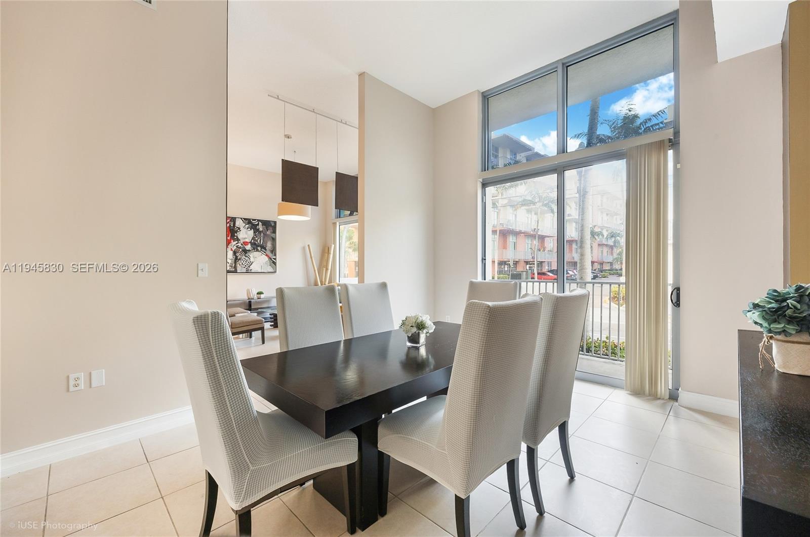 A dining room features a dark wood table, light-colored chairs, and large floor-to-ceiling windows — 140 S Dixie Hwy, Hollywood FL 33020, HOLLYWOOD, FL
