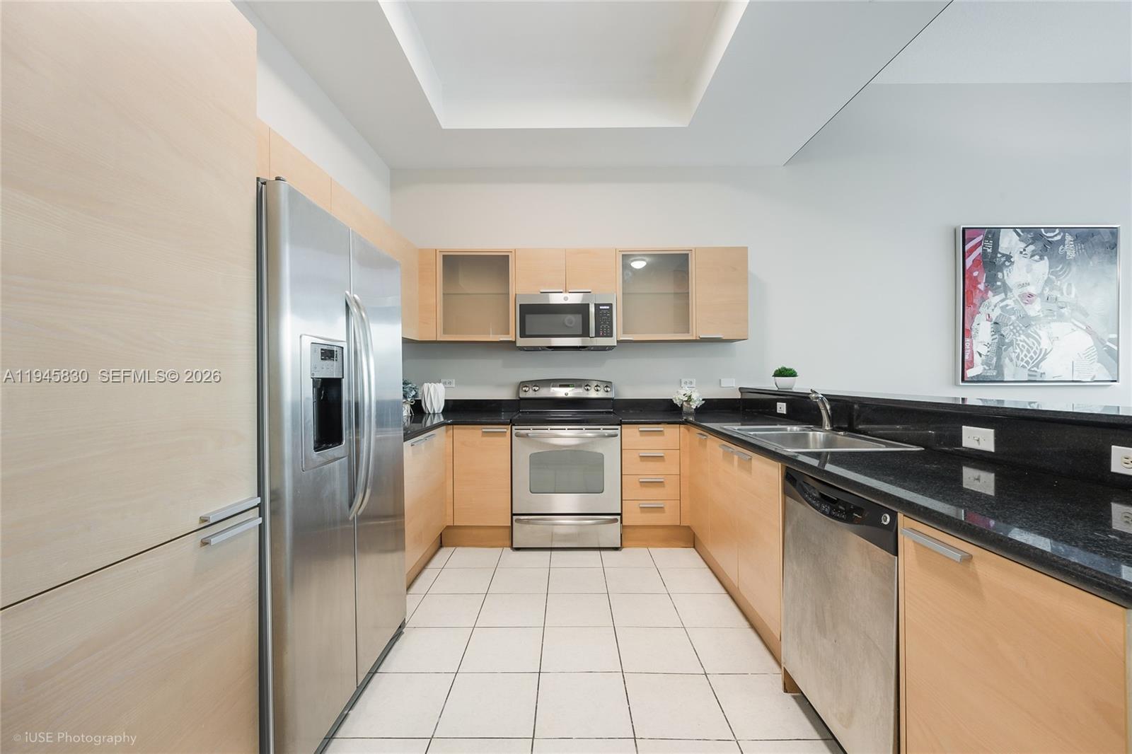 A kitchen features light wood cabinets, black granite countertops, stainless steel appliances, and white tile flooring — 140 S Dixie Hwy, Hollywood FL 33020, HOLLYWOOD, FL