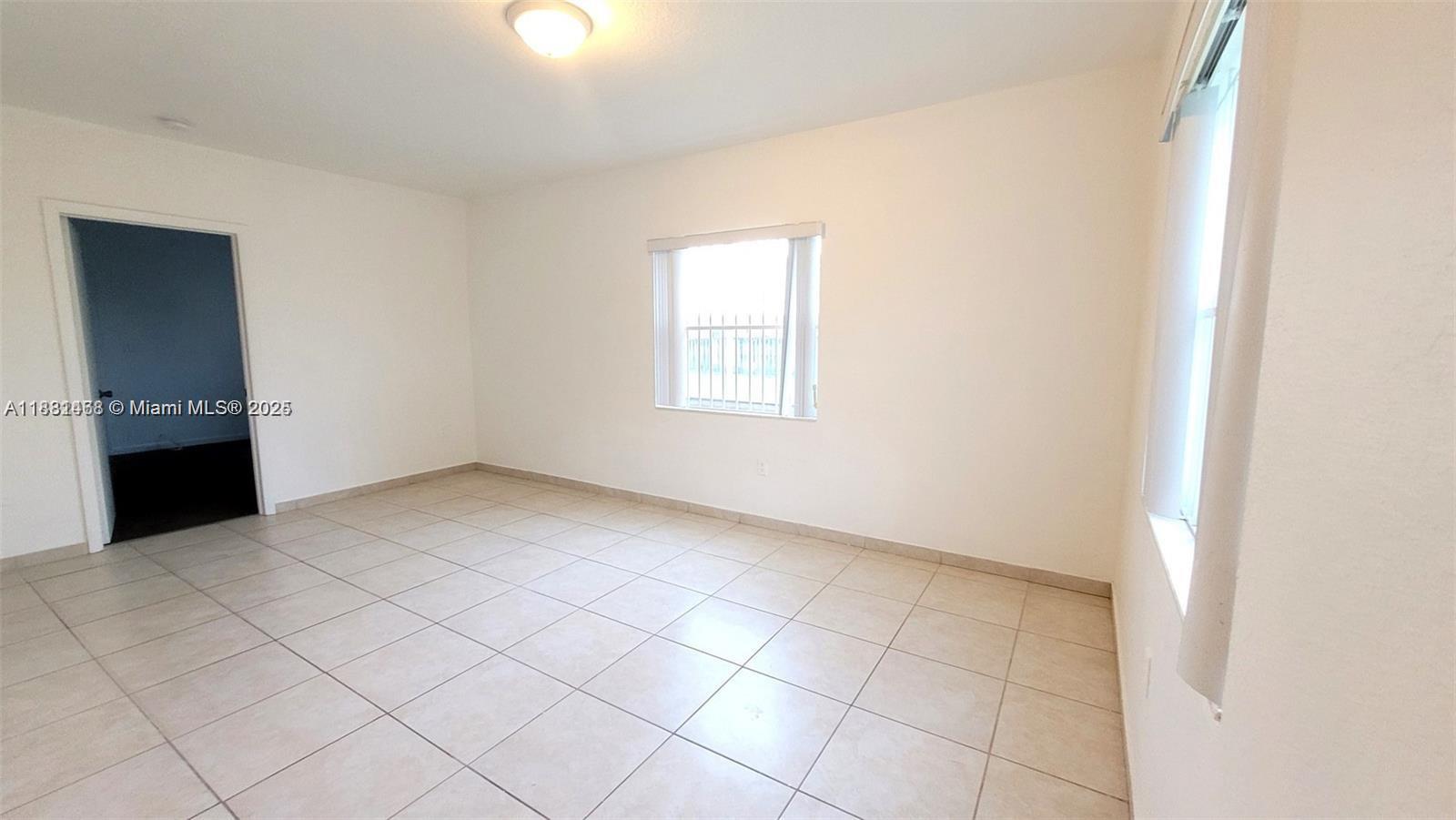 An empty room features white walls, light-colored tile flooring, and a window with security bars — 8453 NW 4th Ct # 8453, Miami FL 33150, MIAMI, FL
