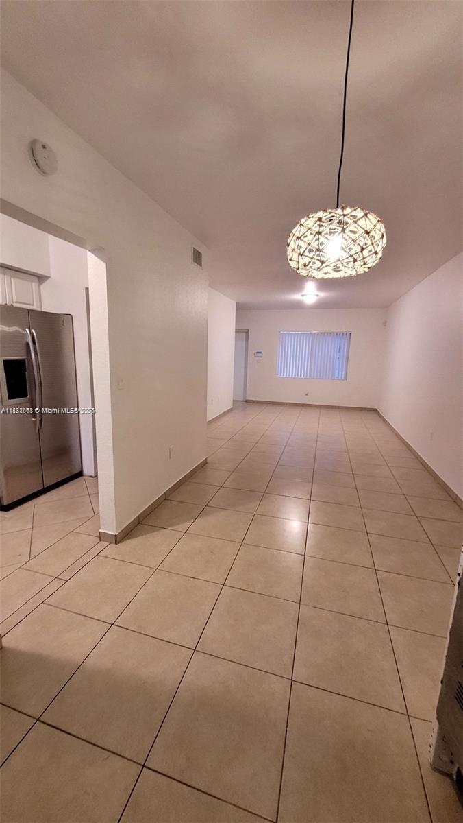 A tiled dining area features a hanging light fixture and an adjacent kitchen with stainless appliances — 8453 NW 4th Ct # 8453, Miami FL 33150, MIAMI, FL