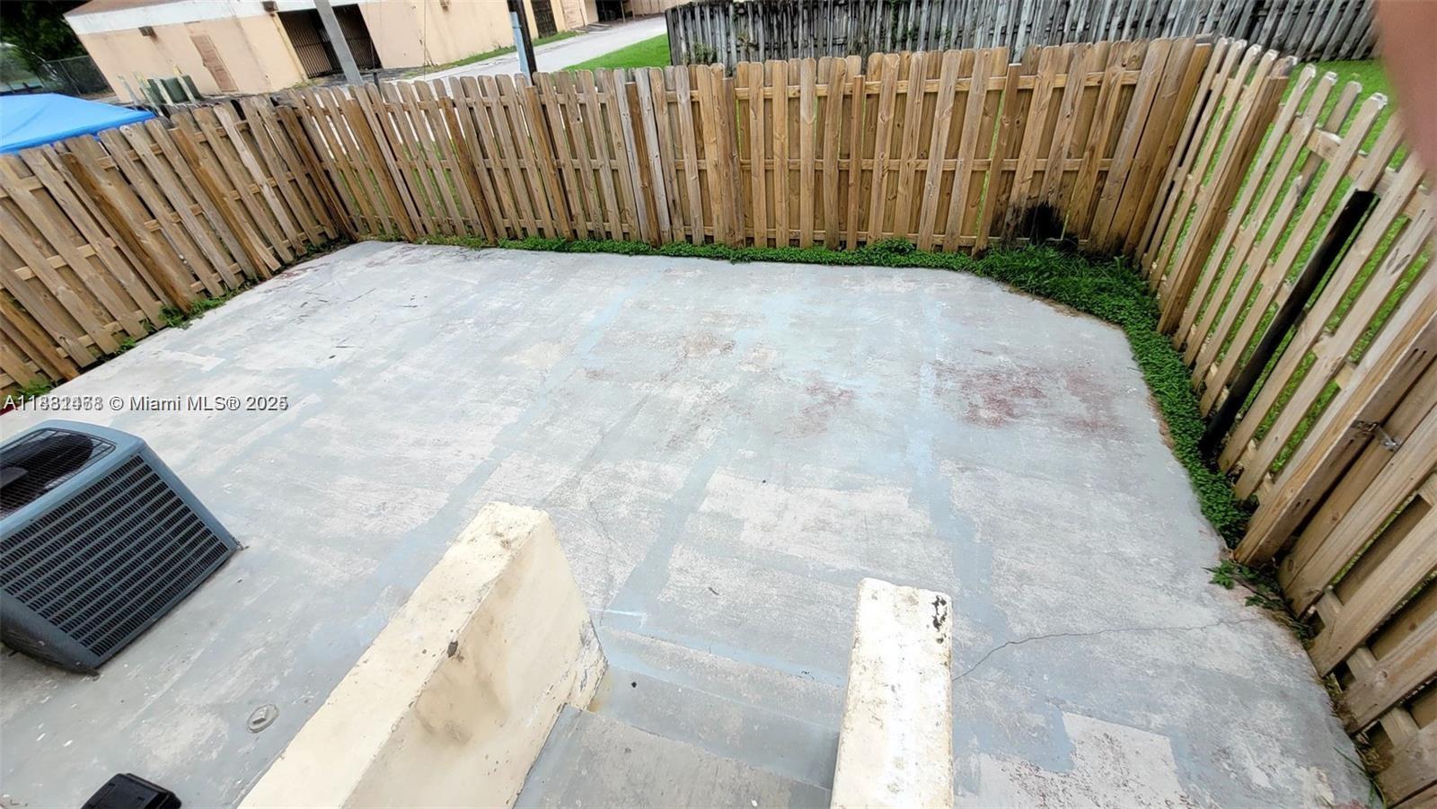 A concrete patio is enclosed by a wooden fence with an air conditioning unit nearby — 8453 NW 4th Ct # 8453, Miami FL 33150, MIAMI, FL