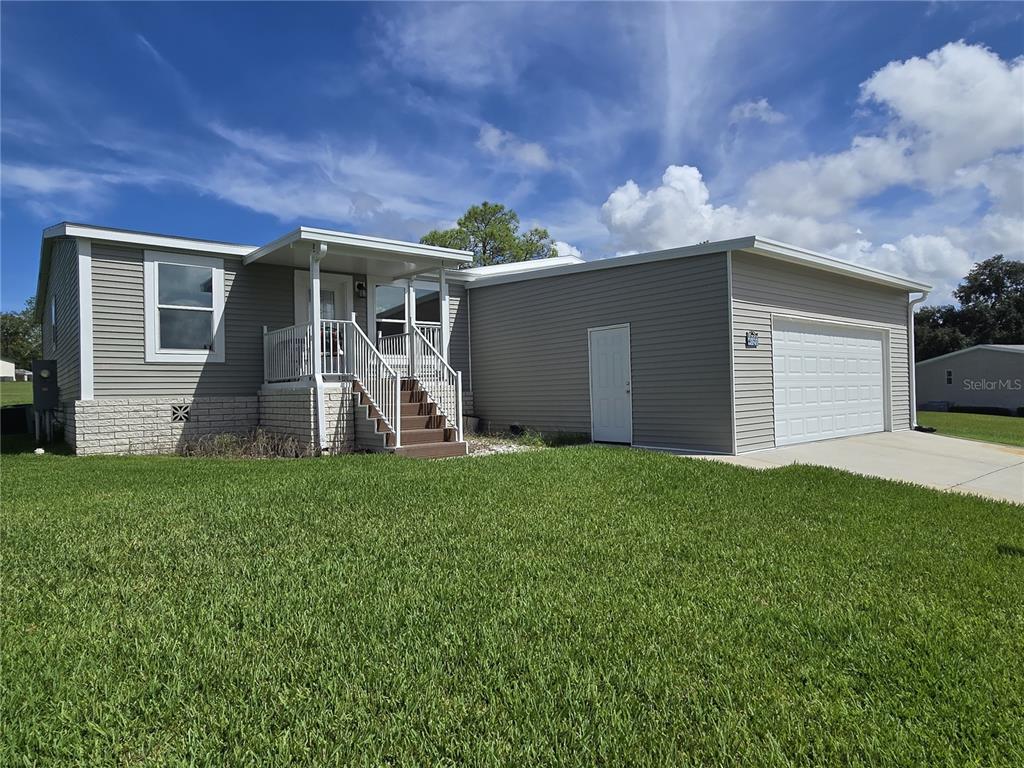 A single-story house with gray siding, a front porch, and an attached two-car garage — 4121 GREENBLUFF ROAD UNIT 1895, ZELLWOOD, FL