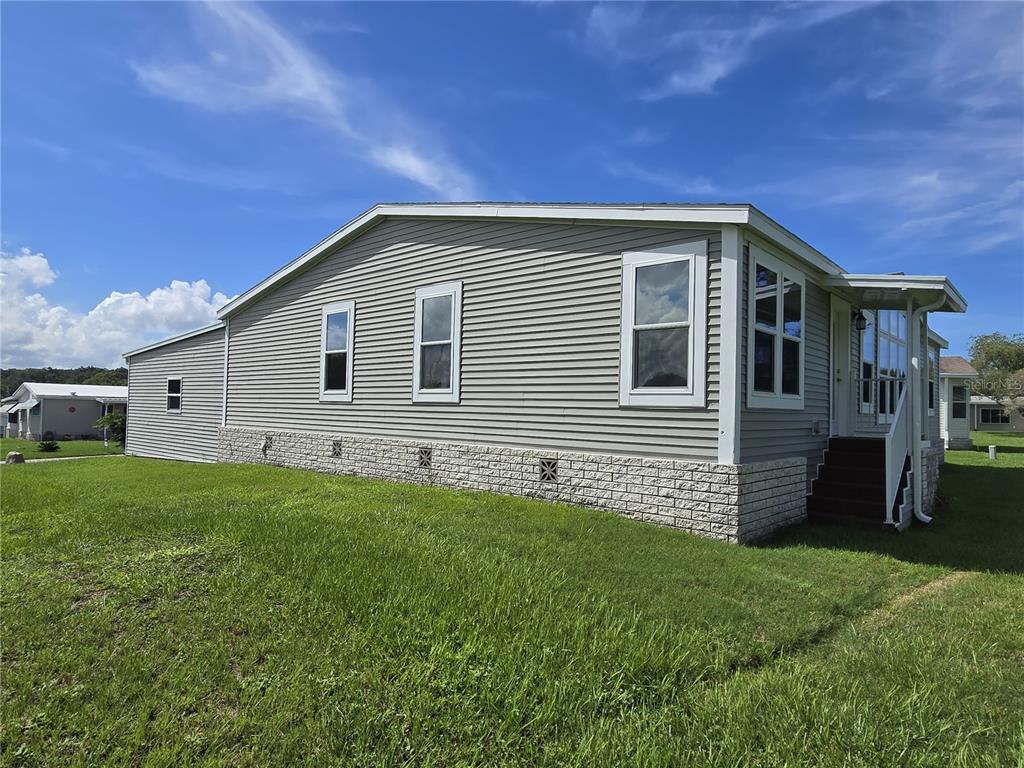 The exterior of a single-story manufactured home features light gray siding and a stone-patterned base — 4121 GREENBLUFF ROAD UNIT 1895, ZELLWOOD, FL