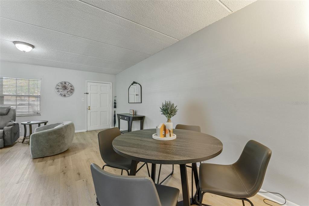 A dining area with a round table and chairs sits in an open-concept living space — 4724 MICHAEL COURT UNIT 123, TAMPA, FL