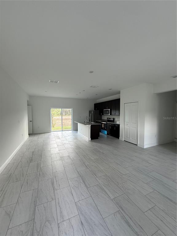 An open-concept kitchen and living area features white tile flooring, dark cabinetry, and sliding doors — 2885 W REDGATE DRIVE, DUNNELLON, FL