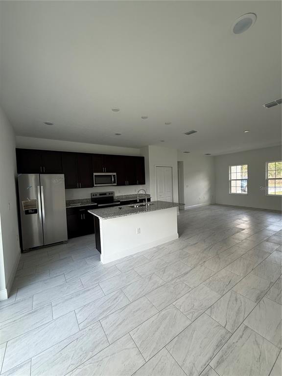 An open-concept living area features white tile floors, a kitchen island, and a ceiling fan — 2885 W REDGATE DRIVE, DUNNELLON, FL
