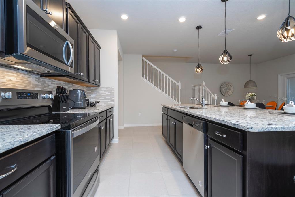 A kitchen features dark cabinets, stainless steel appliances, granite countertops, and a central island — 4178 LANA AVENUE, DAVENPORT, FL