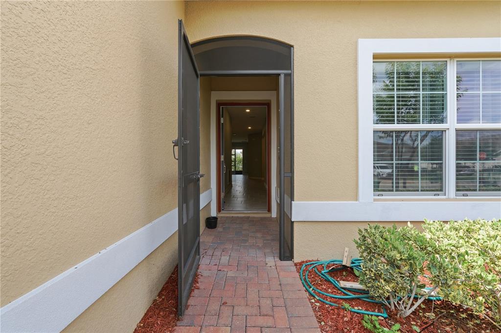 A paved walkway leads to an open front door with a screen door and window — 3023 CANEEL STREET, WINTER HAVEN, FL