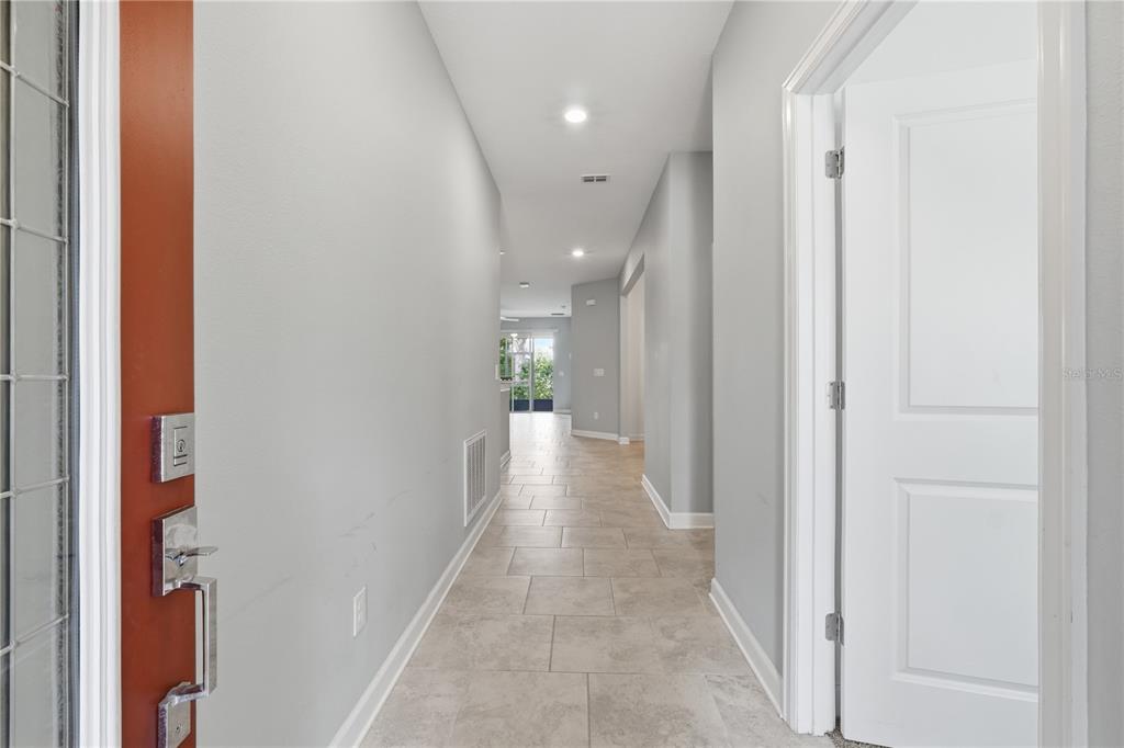 A view from an entryway looking down a tiled hallway toward a bright living area — 3023 CANEEL STREET, WINTER HAVEN, FL
