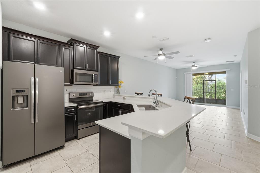 A kitchen with dark cabinets, stainless steel appliances, and a white quartz breakfast bar — 3023 CANEEL STREET, WINTER HAVEN, FL