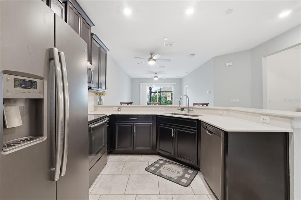A kitchen features dark wood cabinets, stainless steel appliances, and a light-colored countertop — 3023 CANEEL STREET, WINTER HAVEN, FL