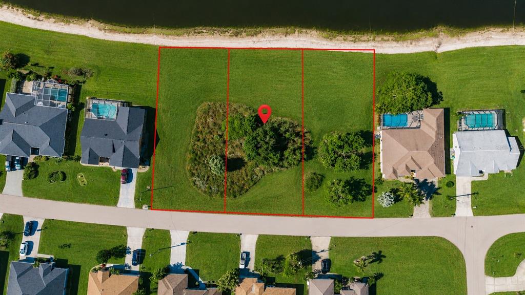 An aerial view shows three adjacent vacant lots with trees, bordering a lake and road — 2361 SOFIA LANE, PUNTA GORDA, FL