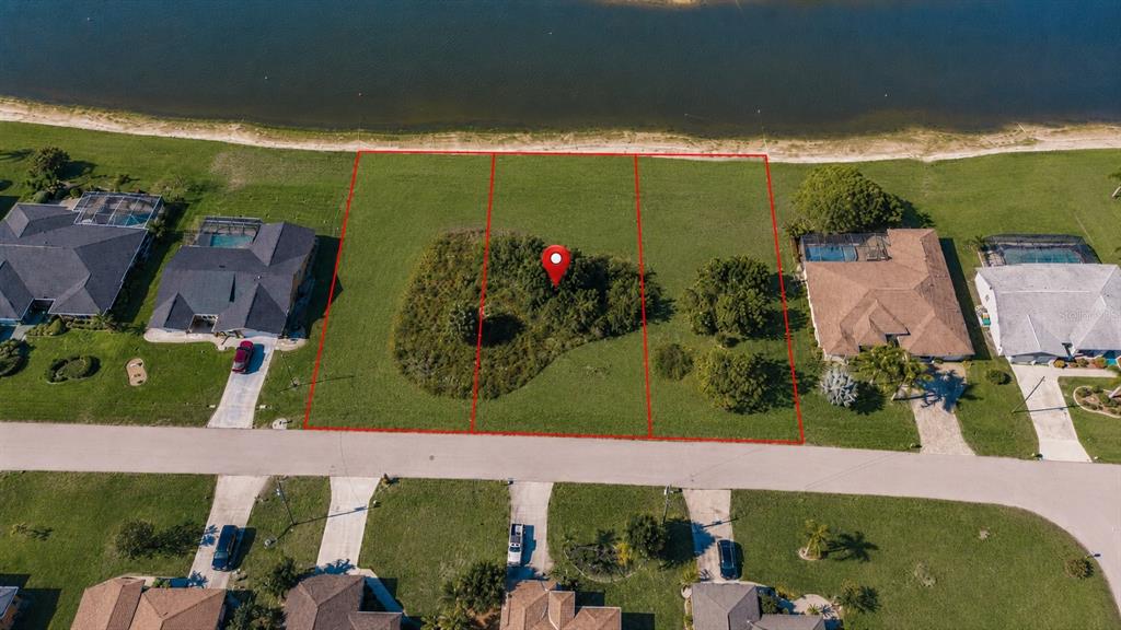 An aerial view shows three vacant waterfront lots outlined in red along a paved road — 2361 SOFIA LANE, PUNTA GORDA, FL