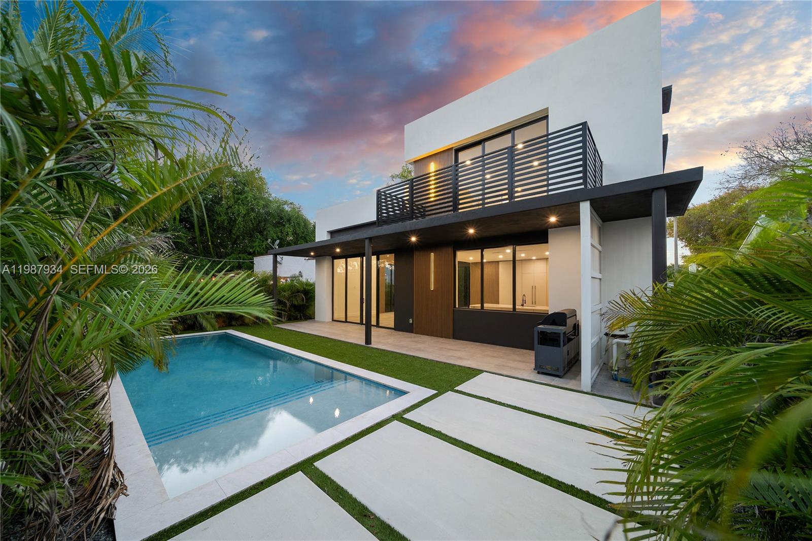 A modern two-story house features a backyard swimming pool, patio, and balcony at sunset — 536 NW 48th ST, Miami FL 33127, MIAMI, FL