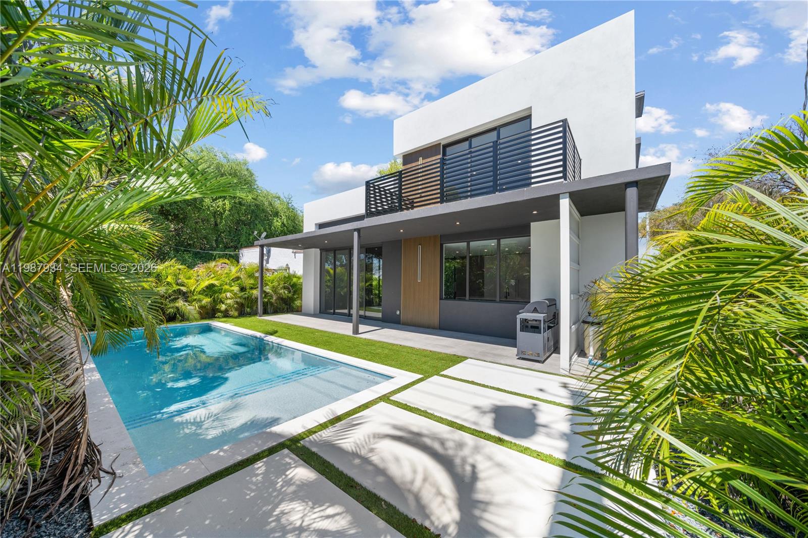A modern two-story house features a swimming pool, a covered patio, and palm trees — 536 NW 48th ST, Miami FL 33127, MIAMI, FL