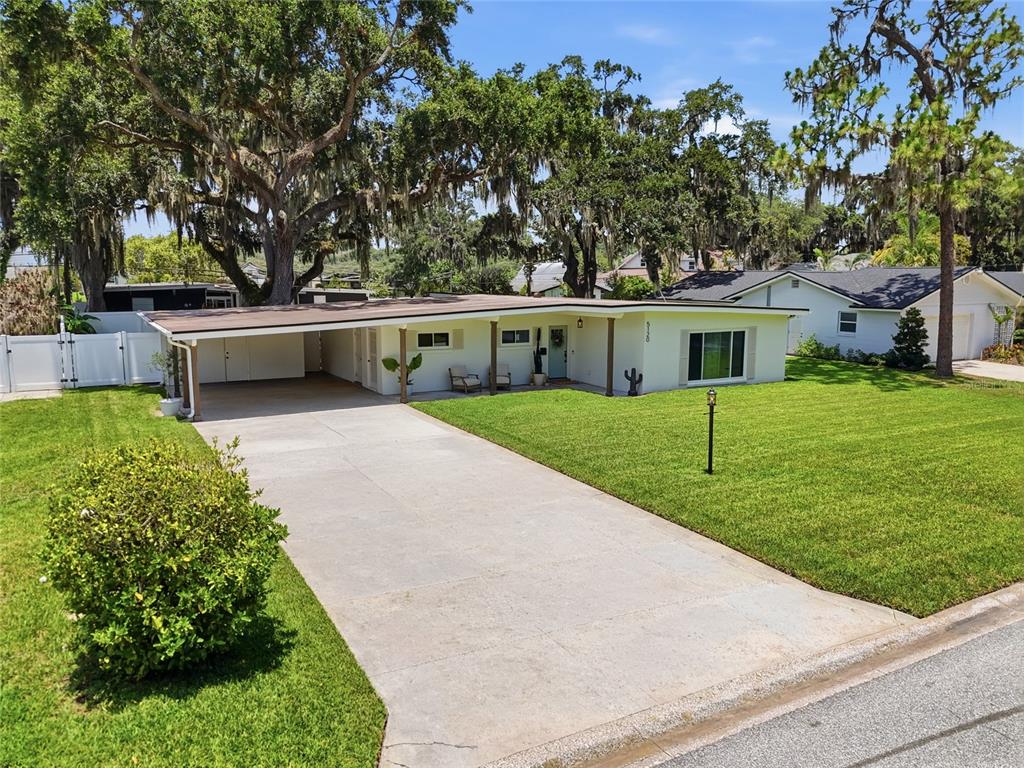 A single-story house with a carport, concrete driveway, and large trees in the front yard — 5120 MORTIER AVENUE, BELLE ISLE, FL