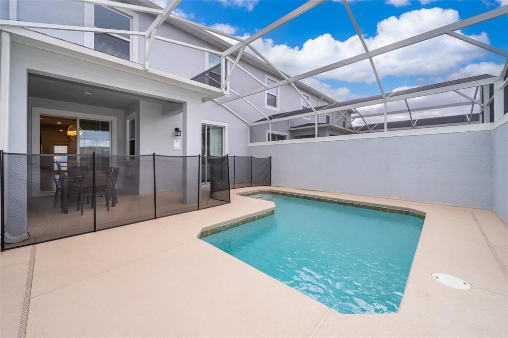 A screened-in patio features a small swimming pool and a black safety fence — 212 OCEAN COURSE AVENUE, DAVENPORT, FL
