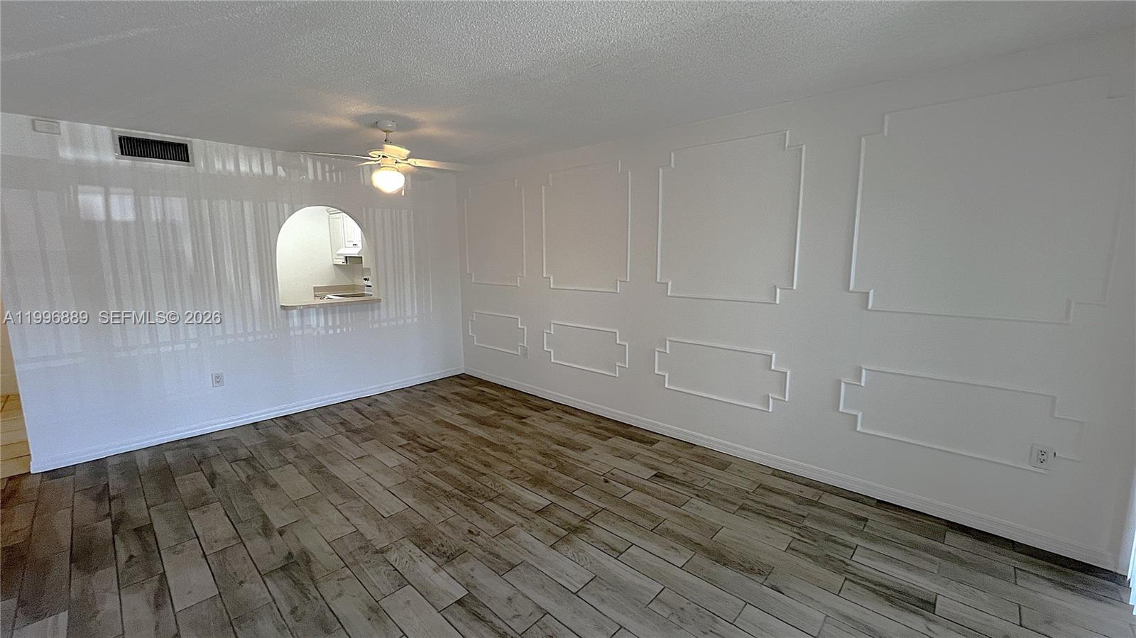An empty room features wood-look tile flooring, white walls with decorative molding, and a ceiling fan — 711 N Pine Island Rd # 211, Plantation FL 33324, PLANTATION, FL