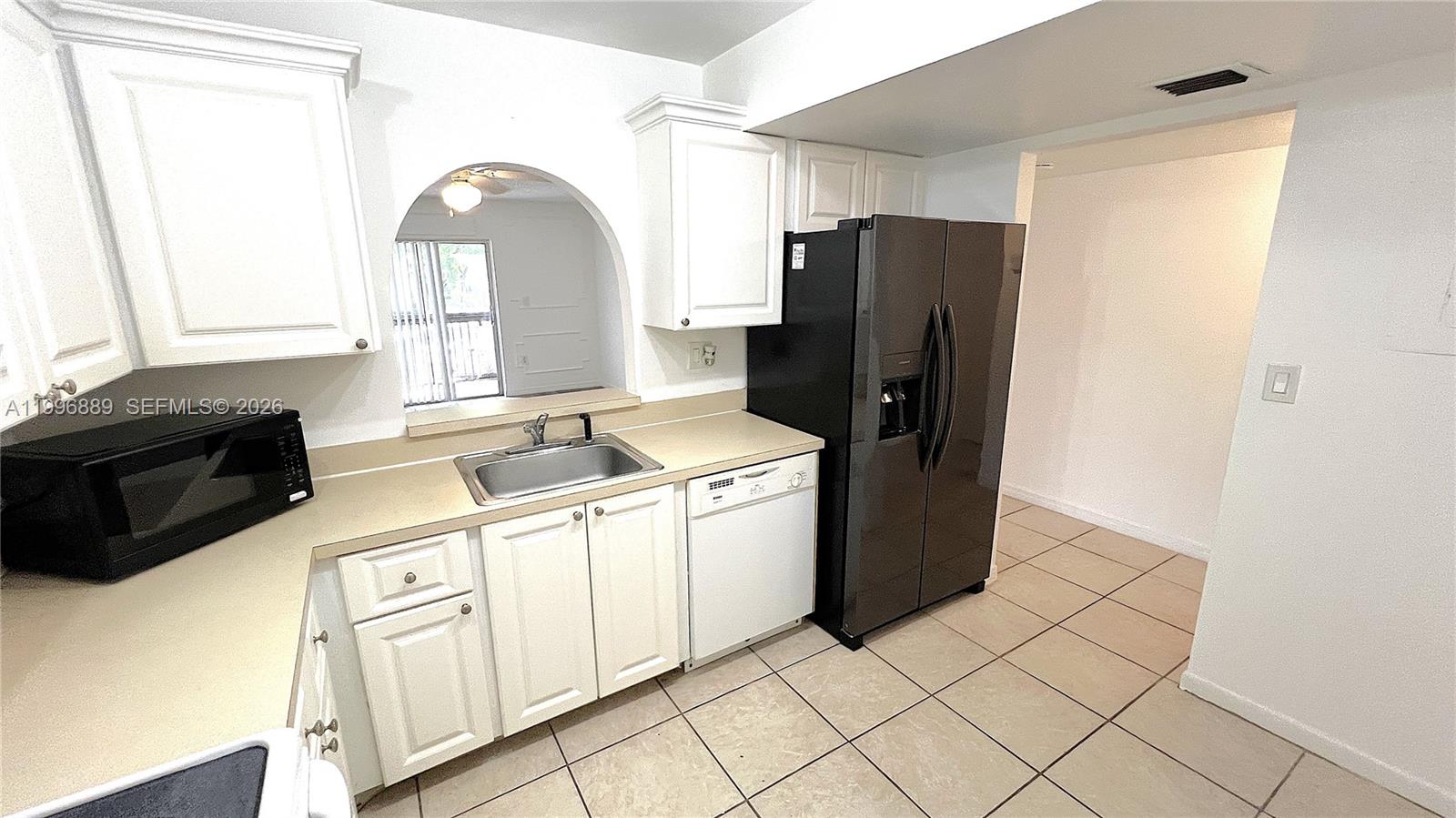A kitchen features white cabinets, a black refrigerator, a dishwasher, and a pass-through window — 711 N Pine Island Rd # 211, Plantation FL 33324, PLANTATION, FL