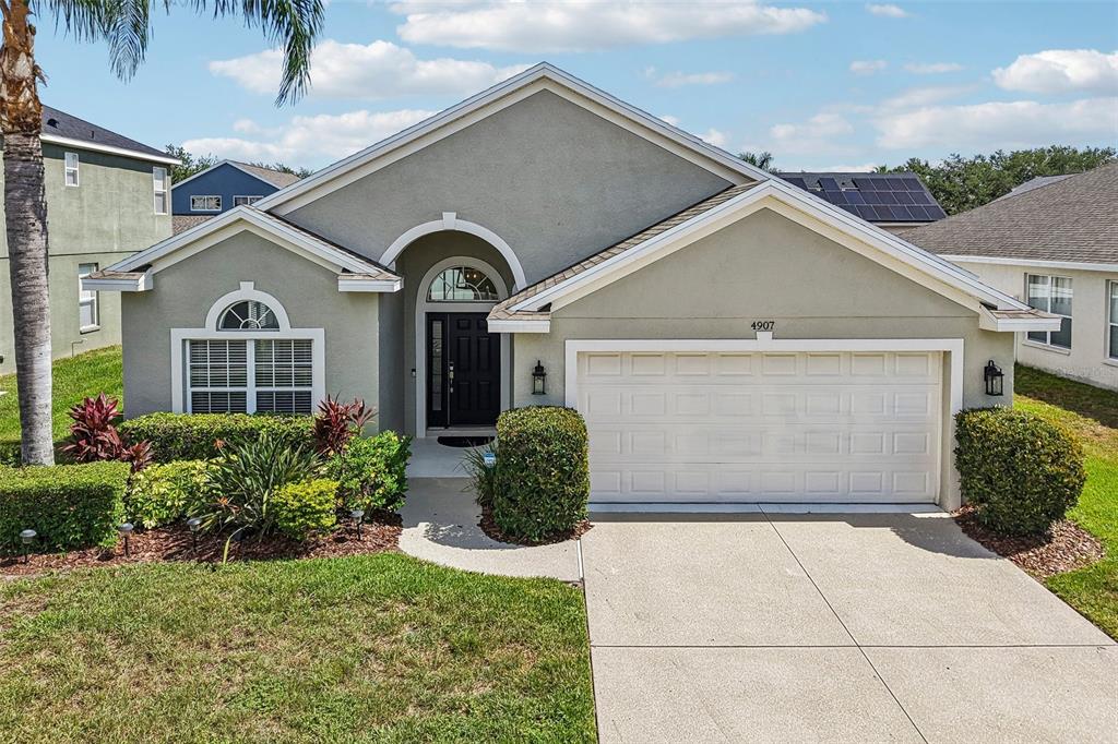 A single-story house with a beige stucco exterior, a two-car garage, and a front walkway — 4907 58TH TERRACE E, BRADENTON, FL