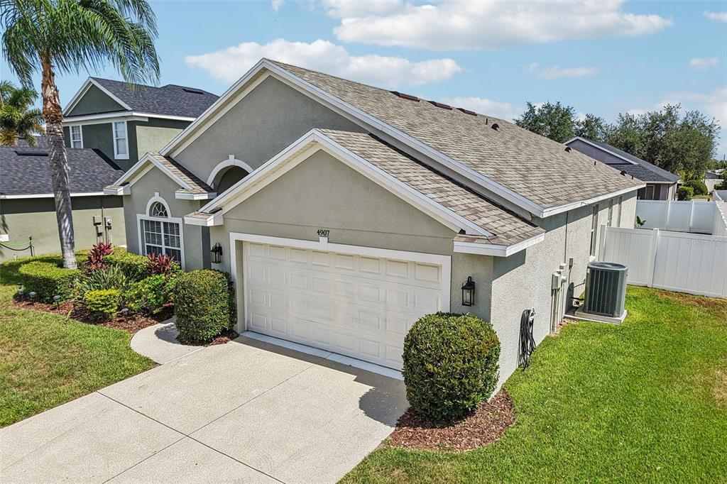 An exterior view of a single-story house with a two-car garage and a palm tree — 4907 58TH TERRACE E, BRADENTON, FL
