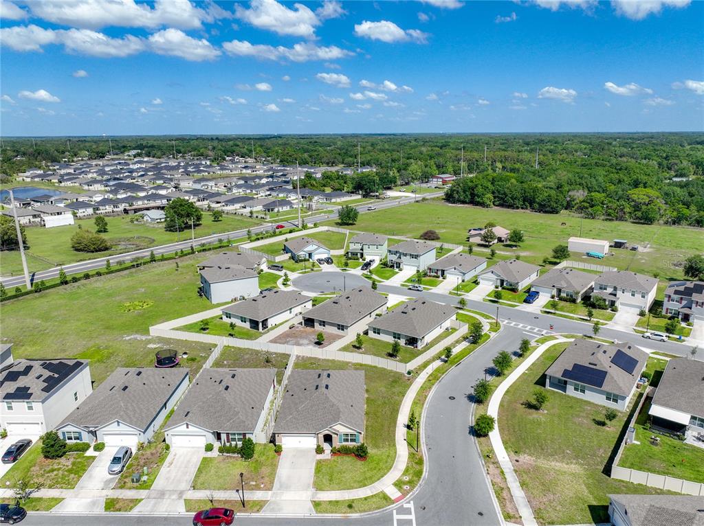 An aerial view shows a suburban neighborhood with single-family homes, paved streets, and green lawns — 3974 MEKONG COURT, ST CLOUD, FL