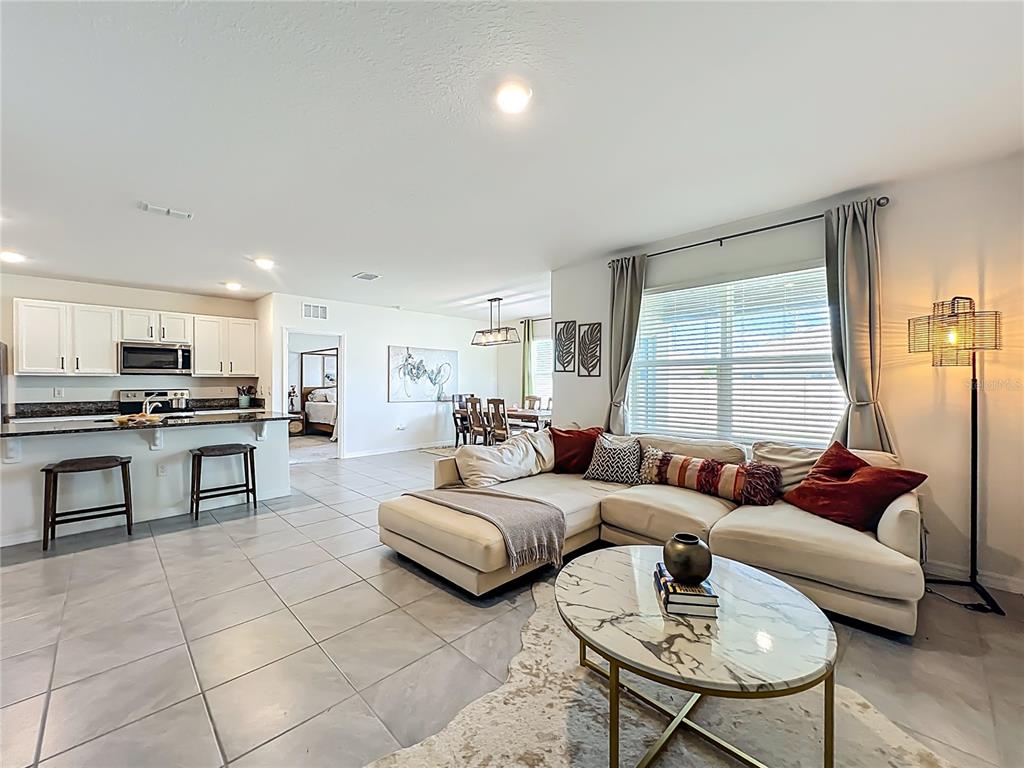 An open-concept living room features a sectional sofa, marble coffee table, and adjacent kitchen — 3974 MEKONG COURT, ST CLOUD, FL