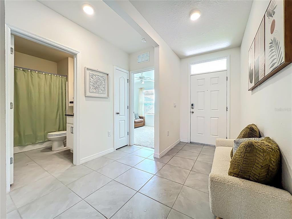 A tiled entryway features a white front door, a bathroom, and a small sofa — 3974 MEKONG COURT, ST CLOUD, FL