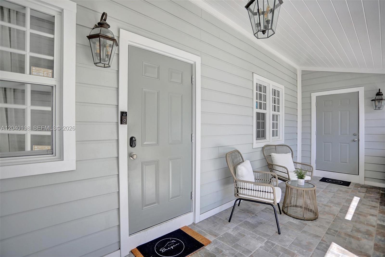 A covered porch features light gray siding, two wicker chairs, a small table, and two doors — 421 NE 70th ST, Miami FL 33138, MIAMI, FL