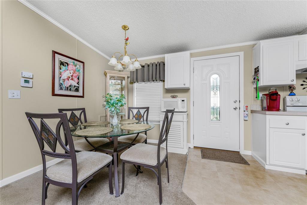 A dining area with a glass table, four chairs, and a white front door — 24437 HARBORVIEW ROAD UNIT 62, PUNTA GORDA, FL