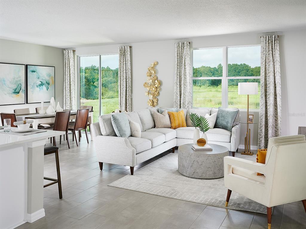 A bright living room features a sectional sofa, round coffee table, and dining area — 100 GENTLE RAIN LANE, NOKOMIS, FL