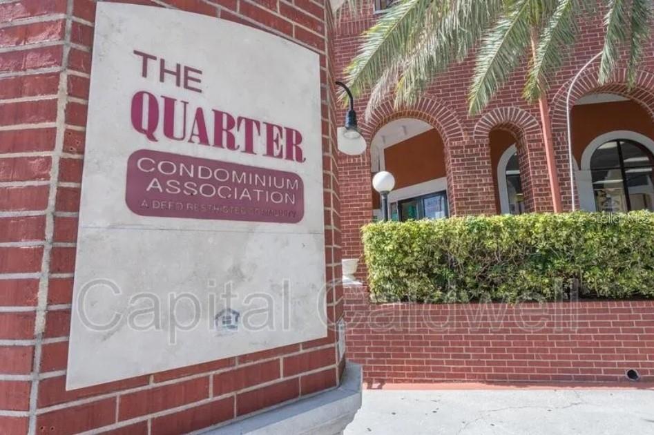 A brick pillar displays a sign for The Quarter Condominium Association near a building entrance — 1910 E PALM AVENUE UNIT 11213, TAMPA, FL